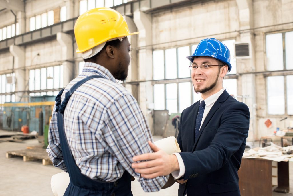 Cheerful businessman collaborating with construction manager